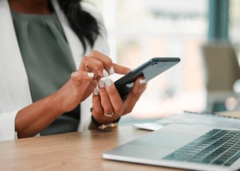 Phone, office and business woman networking on social media, the internet or a mobile app. Technology, corporate and professional company leader browsing on a mobile device in her modern workplace.