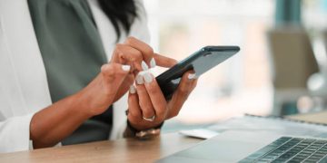 Phone, office and business woman networking on social media, the internet or a mobile app. Technology, corporate and professional company leader browsing on a mobile device in her modern workplace.